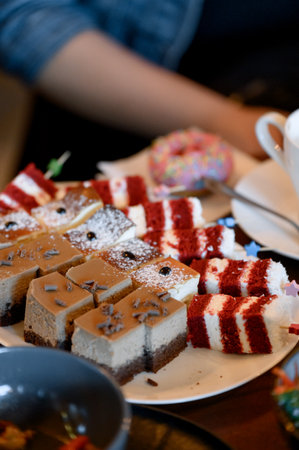 Close-up of a selection of red velvet cakes and caramel cheesecake on a white plate. Multicolored portioned pieces of cakes and pastries for the dessert tableの写真素材