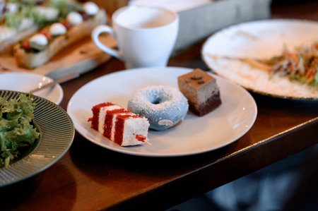 An assortment of pastries and a glazed donut on a plate. Close-up of a plate with various portioned...
