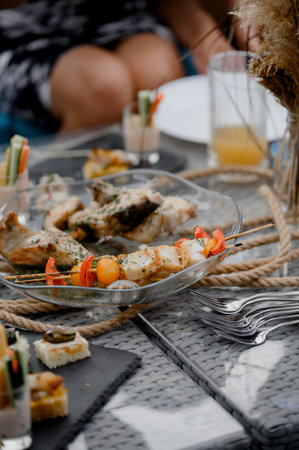 Close-up of a clear dish with baked fish pieces and vegetable skewers with herbs. Assorted fried fish and chicken kebabs with red pepper and herbs on a glass plate.の写真素材