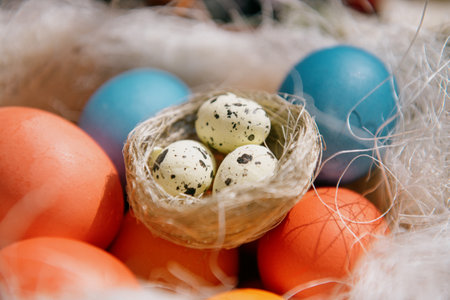 Close-up of quail eggs among a pile of Easter eggs. Spring Easter decor with an artificial nest and...