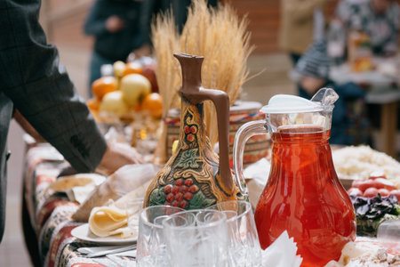A table with a jug of red drink at a traditional festival. Traditional Caucasian or Eastern dishes with drinks on a set tableの写真素材