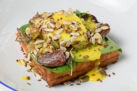 Salty waffle with poached egg, beef and sunflower seeds in sauce close-up, A hearty breakfast with...