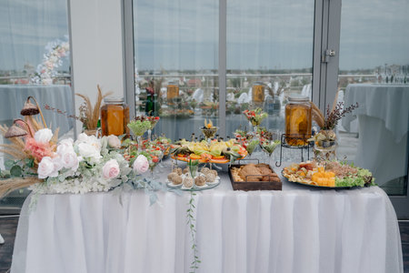 A long buffet table with plenty of appetizers, canapes, and sandwiches. Festive table with tiered...