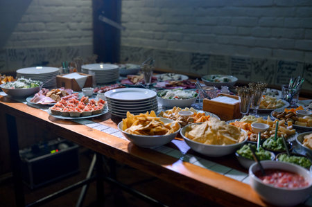 A buffet of appetizers, chips, dips, salads and cold cuts. A festive dinner with buffet food,...