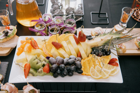 Fruit assortment of pineapple, orange, strawberry, grapes and kiwi.Serving a dessert plate with pineapple, berries, and citrus for holiday cateringの写真素材