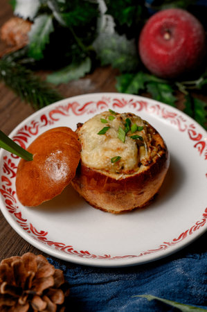 Julienne with melted cheese and green onions inside a toasted bun. Creamy mushroom julienne in a golden bun with herbs on a wooden table with winter decorの写真素材