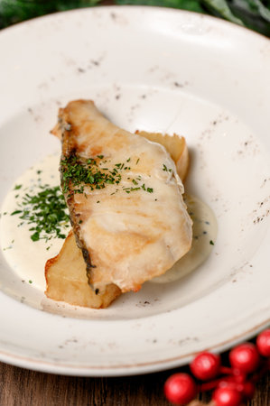 White fish steak with herbs and potato garnish. A serving of baked fish fillet with parsley and...