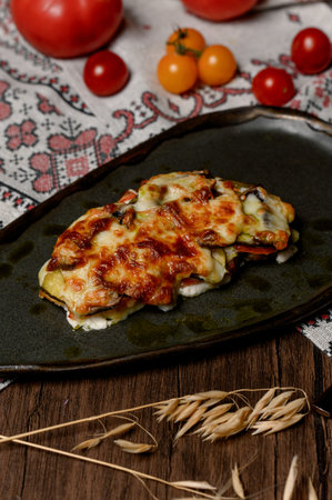 Meat with a golden cheese crust and drops of butter. A ready-made baked dish with vegetables under a layer of fried cheese for a festive dinner.の写真素材