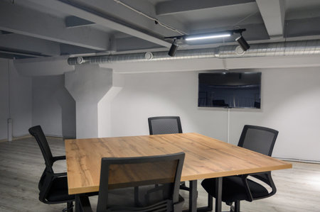 Modern meeting room with a wooden table, black chairs and a TV on the wall. Interior of an office...