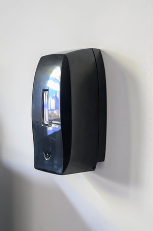 Automatic touch dispenser made of black plastic. A modern touchless hand sanitizer dispenser mounted...
