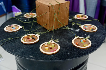 Decorative pendants with colorful beads are arranged around a wooden box on a black table, showcasing a unique design and craftsmanshipの写真素材