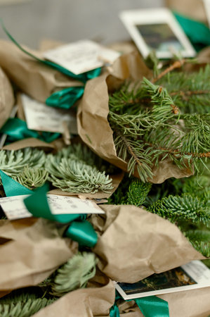 Bundles of evergreen branches are wrapped in brown paper with green ribbons and tags, showcasing a...