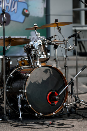 Close-up of a drum set featuring a bass drum, cymbals, and microphone, positioned on stage with a...