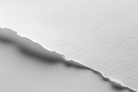 A close-up view of a torn edge of white paper, showcasing its textured surface.の素材