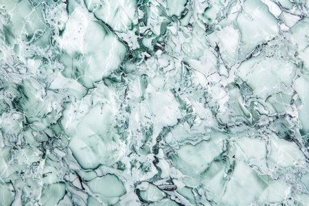 A close-up of a polished green and white marble surface with intricate veining and swirls.の素材