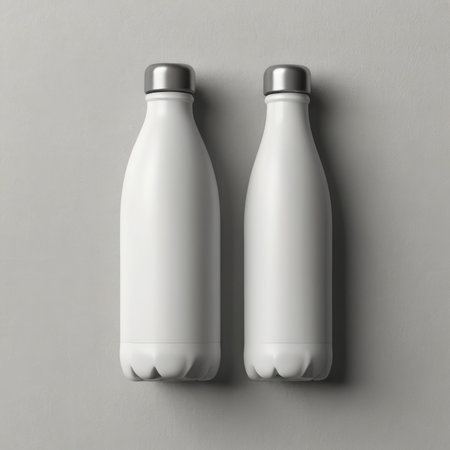 A high angle view shows two blank white bottles with silver caps on a gray background.の素材