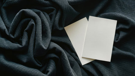 Blank business cards on black fabric background. Mockup for branding identity.の素材