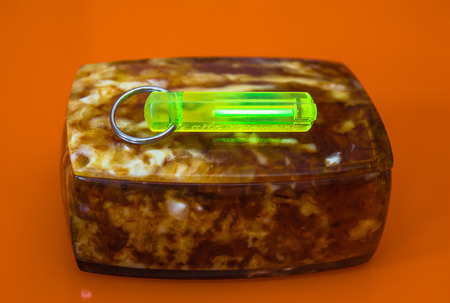 Green glowing tritium radioactive trinket on amber boxの写真素材
