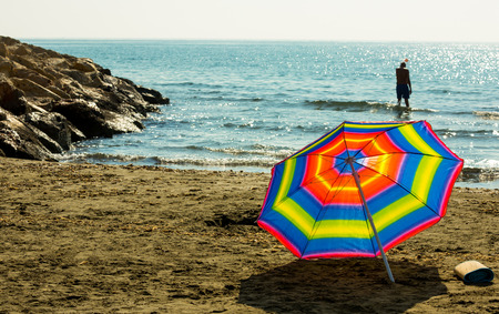 Rainbow beach umbrella on sand on the background of warm Mediterranean Sea in Cyprus Larnacaの写真素材
