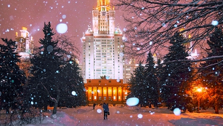 Snowfall in the evenng winter campus of famous Russian university with snowed evergreen trees in...