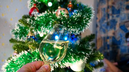 Transparent drinking glasses of sparkling wine on background of illuminated New Year tree with balls and toysの写真素材