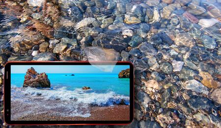 Collage of sunny jellyfish floating in water above Black sea stones and cell phone displaying sunny Cyprus sea landscapes on screen in summerの写真素材