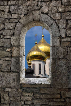 Collage computer image with stone war tower window and sunny golden cupola of orthodox church