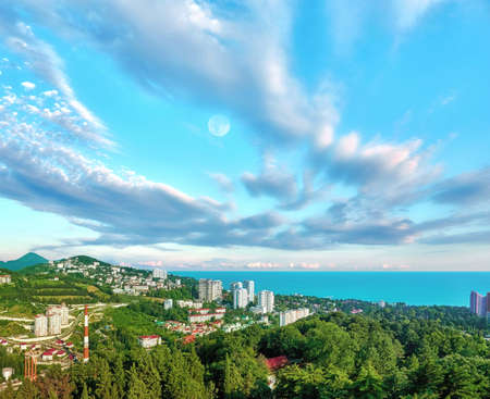 Aerial view of blue coast of Black Sea near Sochi city with residential houses and recreation area under dramatic cloudy sky in sunny summerの写真素材