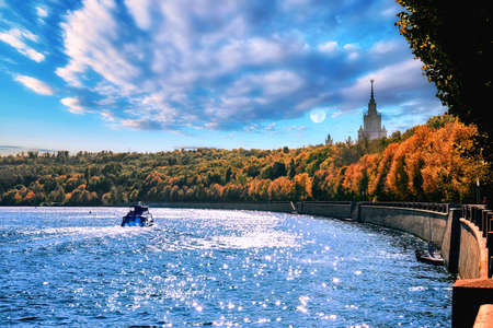 Floating tourist boat and Moscow riverside in early autumn evening under dramatic cloudy skyの写真素材