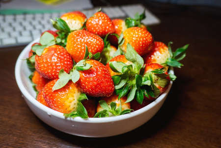 Juicy strawberry on white ceramic plate close up