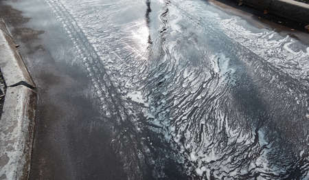 Wet soaped asphalt road in spring Moscow close upの写真素材