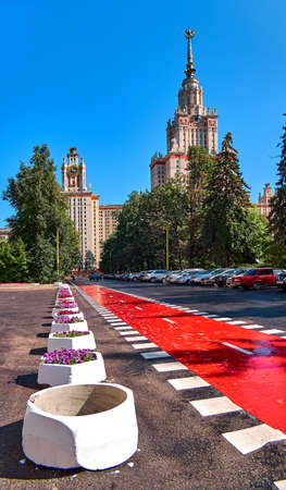 Moscow, Russia - May 9 2019: Red bike road in campus of Moscow university with evergreen trees under dramatic skyのeditorial素材