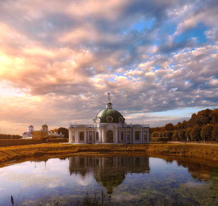 Moscow, Russia - August 2 2020: Picturesque Grotto Pavilion and its water reflection in swamped pond in Kuskovo manor park in autumn Moscow under dramatic sunset sky.のeditorial素材