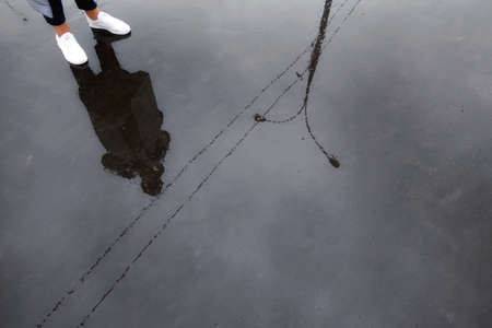 Water reflections of Moscow street, girl and her legs in wet rainy asphalt roadの写真素材