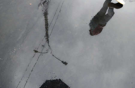 Water reflections of Moscow street and girl in wet rainy asphalt roadの写真素材