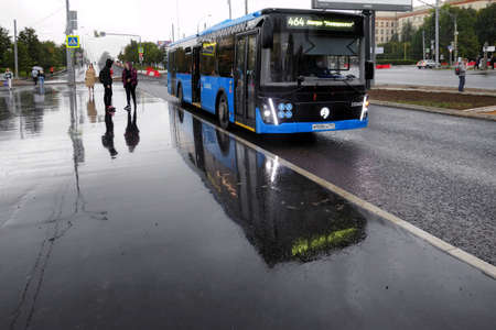 Moscow, Russia - September 5 2021: Water reflections of Moscow street in wet rainy asphalt road with people and blue bus on Moscow streetのeditorial素材