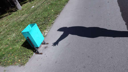 Human hand silhouette and green garbage urn on Moscow road under bright sunlightの写真素材