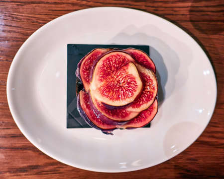 Sweet red figs slices on white dish close up in Moscow cafeの写真素材