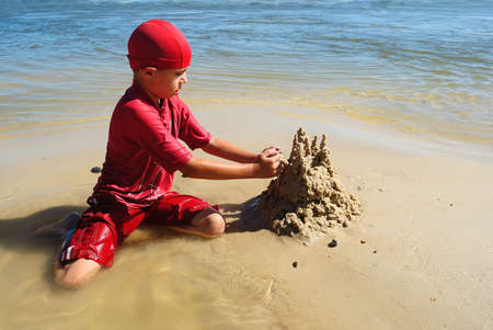  A young boy builds a sand castle on the beachの写真素材