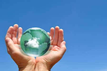 Globe in human hand against blue sky environmental protection conceptの写真素材