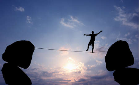 Highline walker in blue sky between two rocks concept of risk taking and challengeの写真素材