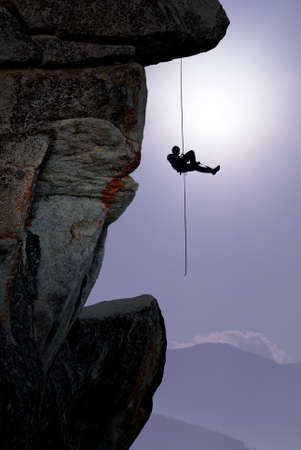 Silhouette of rock climber over blue sky backgroundの写真素材