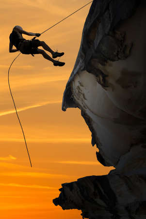 Man rock climber silhouette over bright sunsetの写真素材