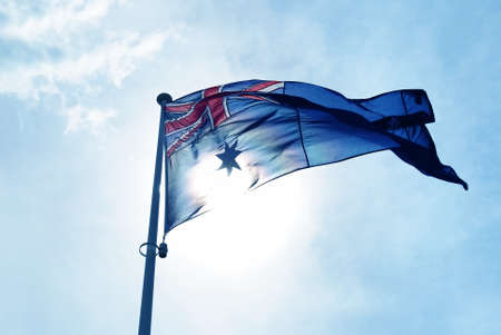 Australian flag blows in the wind against blue sky background