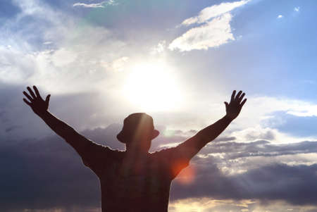Men welcoming sunrise with raised hands concept of Spirituality and Inspirationの写真素材