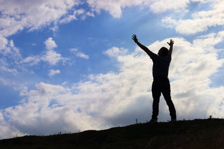Man welcoming sunrise with raised hands concept of Spirituality and Inspirationの写真素材