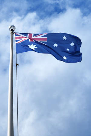 Australian flag blows in the wind against blue sky backgroundの写真素材