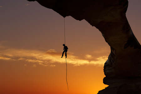 Man rock climber silhouette over bright sunset