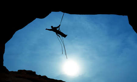 Man rock climber silhouette over blue sky backgroundの写真素材