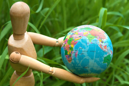 Eearth globe in hands of wooden doll green energy and environmental protection conceptの写真素材